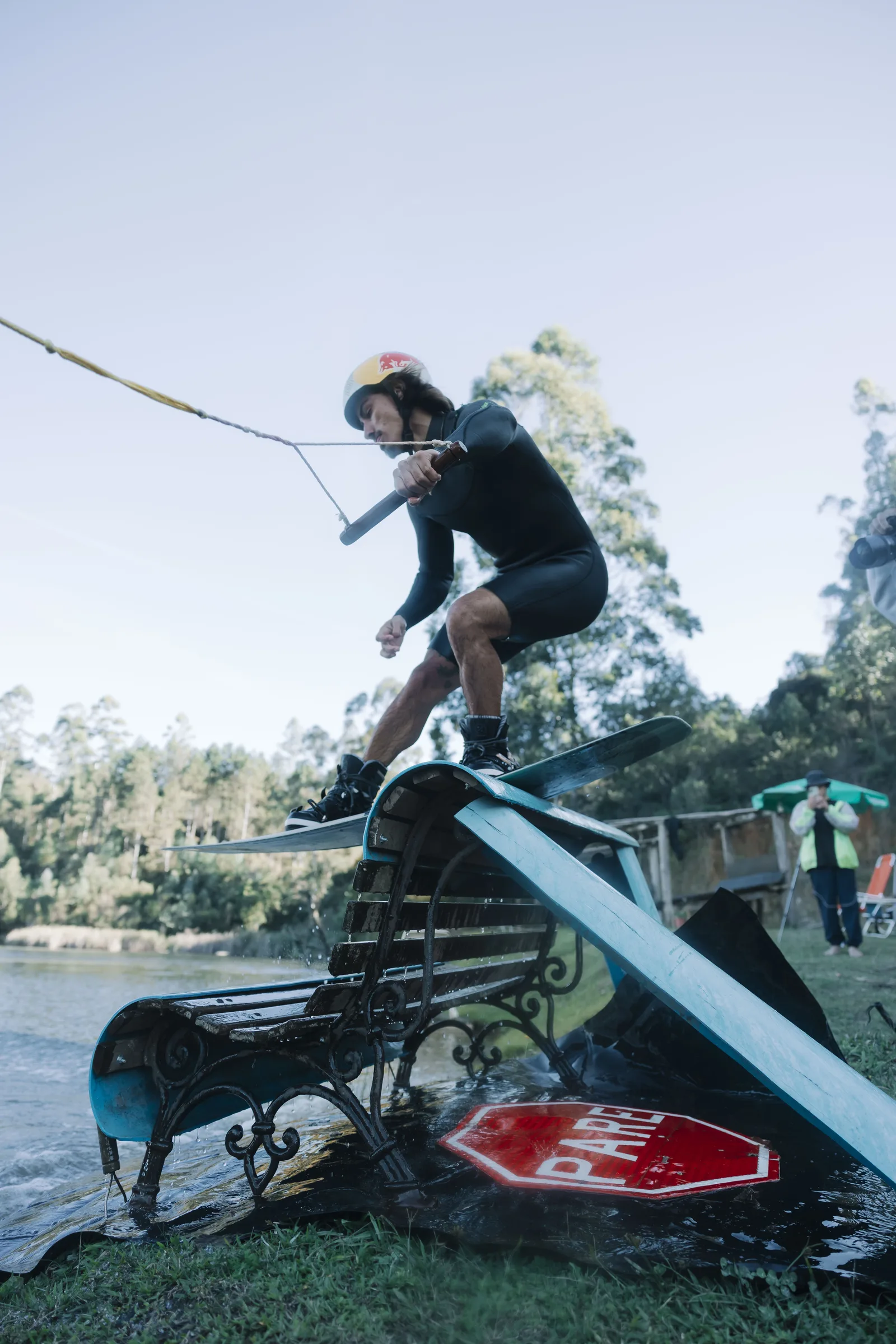 Pedro Caldas em manobra de wakeboard sobre o obstáculo de banco com placa PARE no Blind Wake Club, em Campina Grande do Sul (PR)