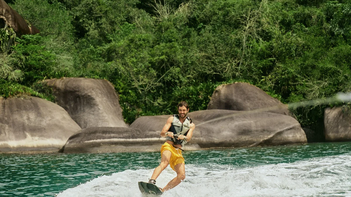 Wakeboarder em ação na enseada do Club Med Rio das Pedras, entre pedras e Mata Atlântica