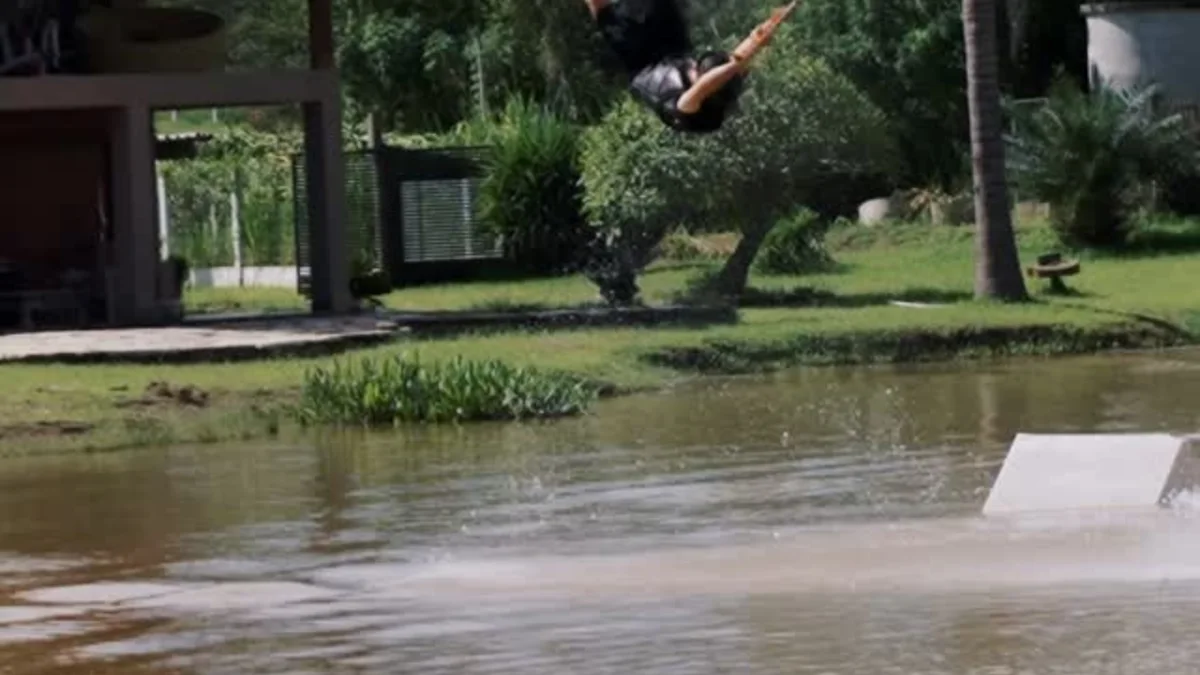 Rider saltando sobre o lago do Ohana Cable, com obstáculo e estrutura do park ao fundo