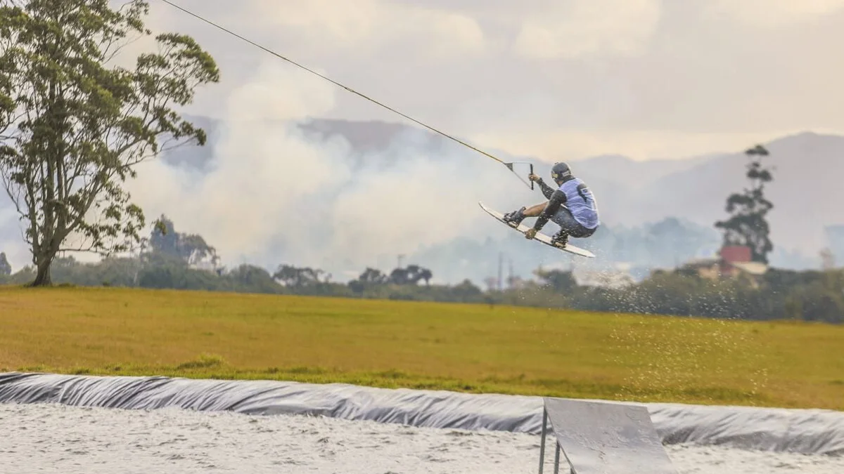 Rider saltando no SkyZimba Cable Park em Imbituba com cabo, lago e obstáculo ao fundo